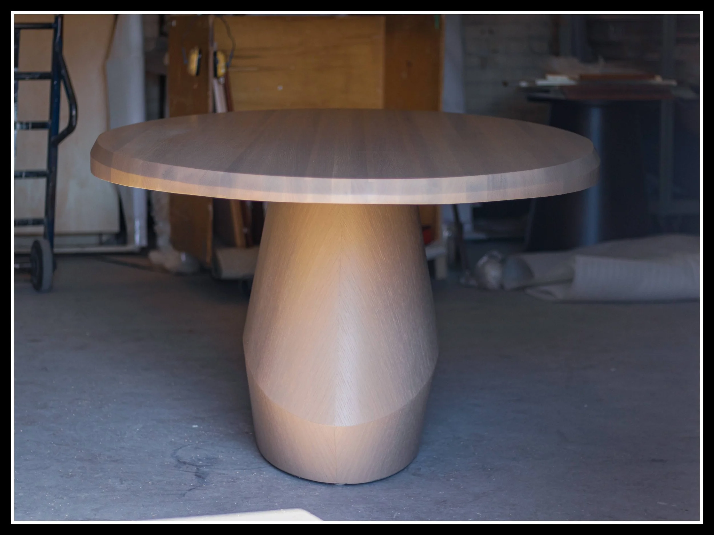 Round red oak table with a tapered underside that lightens the visual weight of the edge profile.