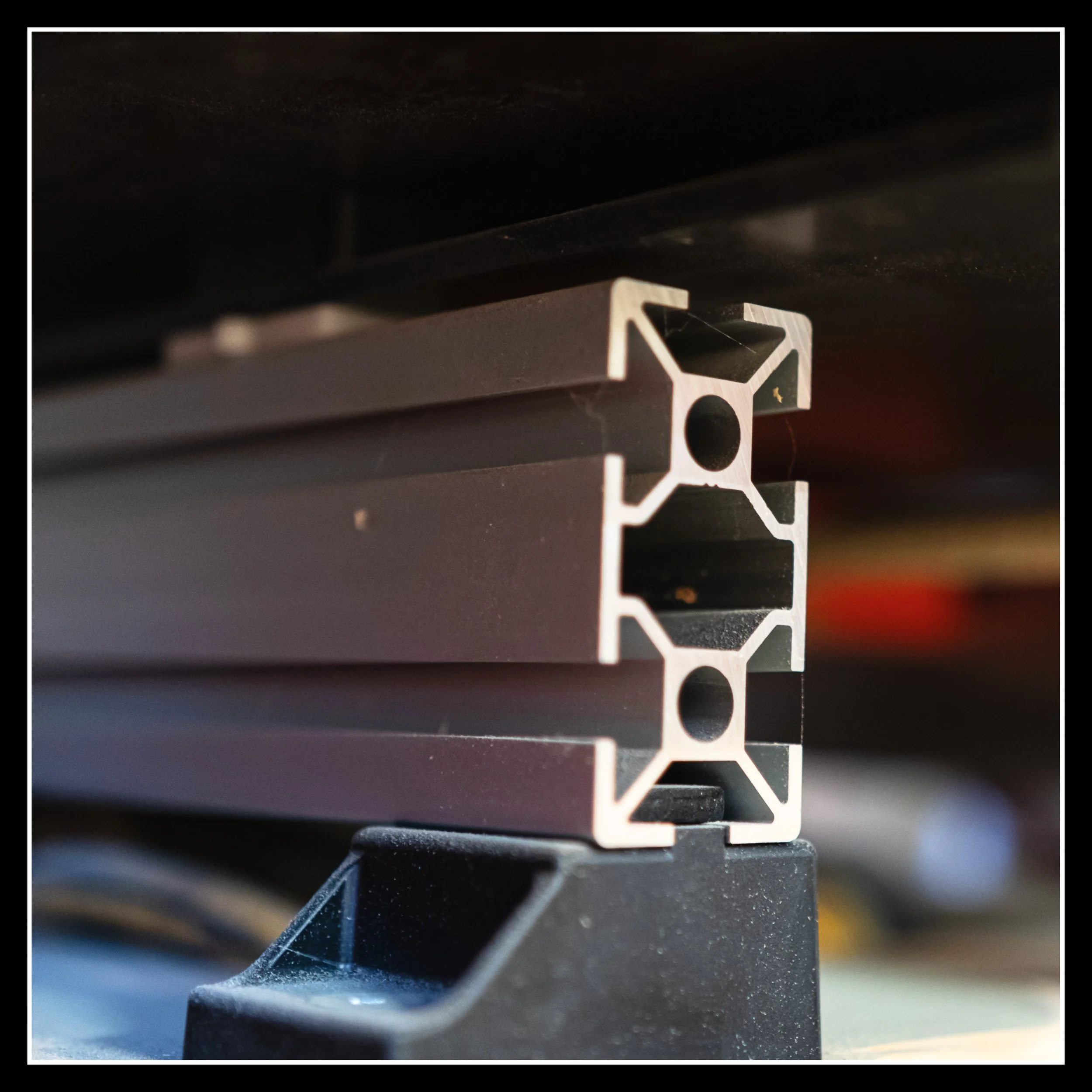 Close‑up of the aluminum extrusion on the Blum Minipress, showing the T‑slot profile, machined edges, and mounting base that supports the precision drilling system in the shop.