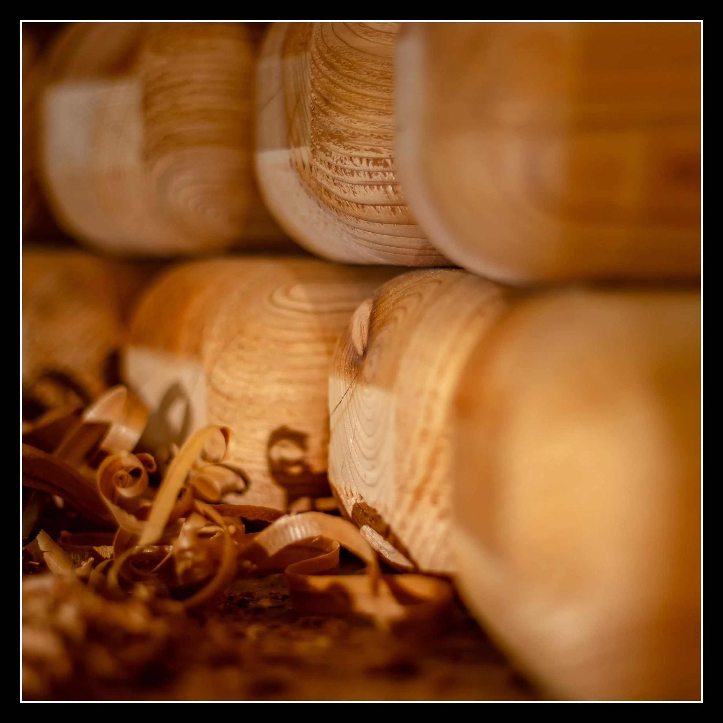 Close-up of stacked cedar yoga blocks with wood shavings at the bottom.