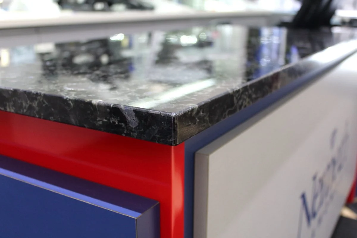 Jewellery store transaction desk with granite countertop and red‑and‑blue commercial cabinetry built to withstand heavy traffic and long‑term use.