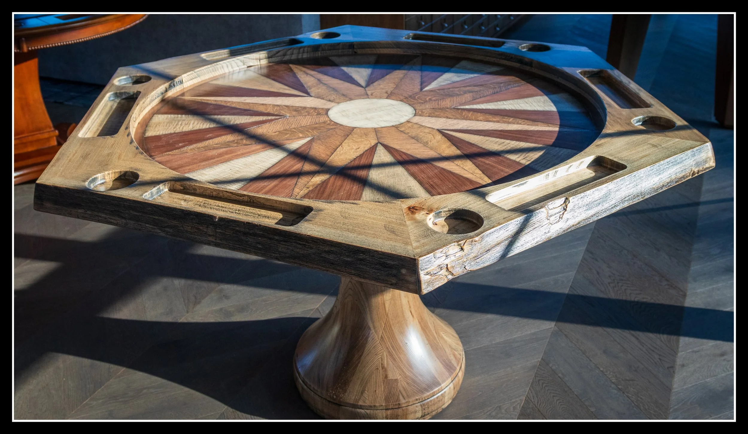 Hexagonal games table with turned maple pedestal, solid elm racetrack, and starburst veneer top made from walnut, maple, red oak, and white oak.