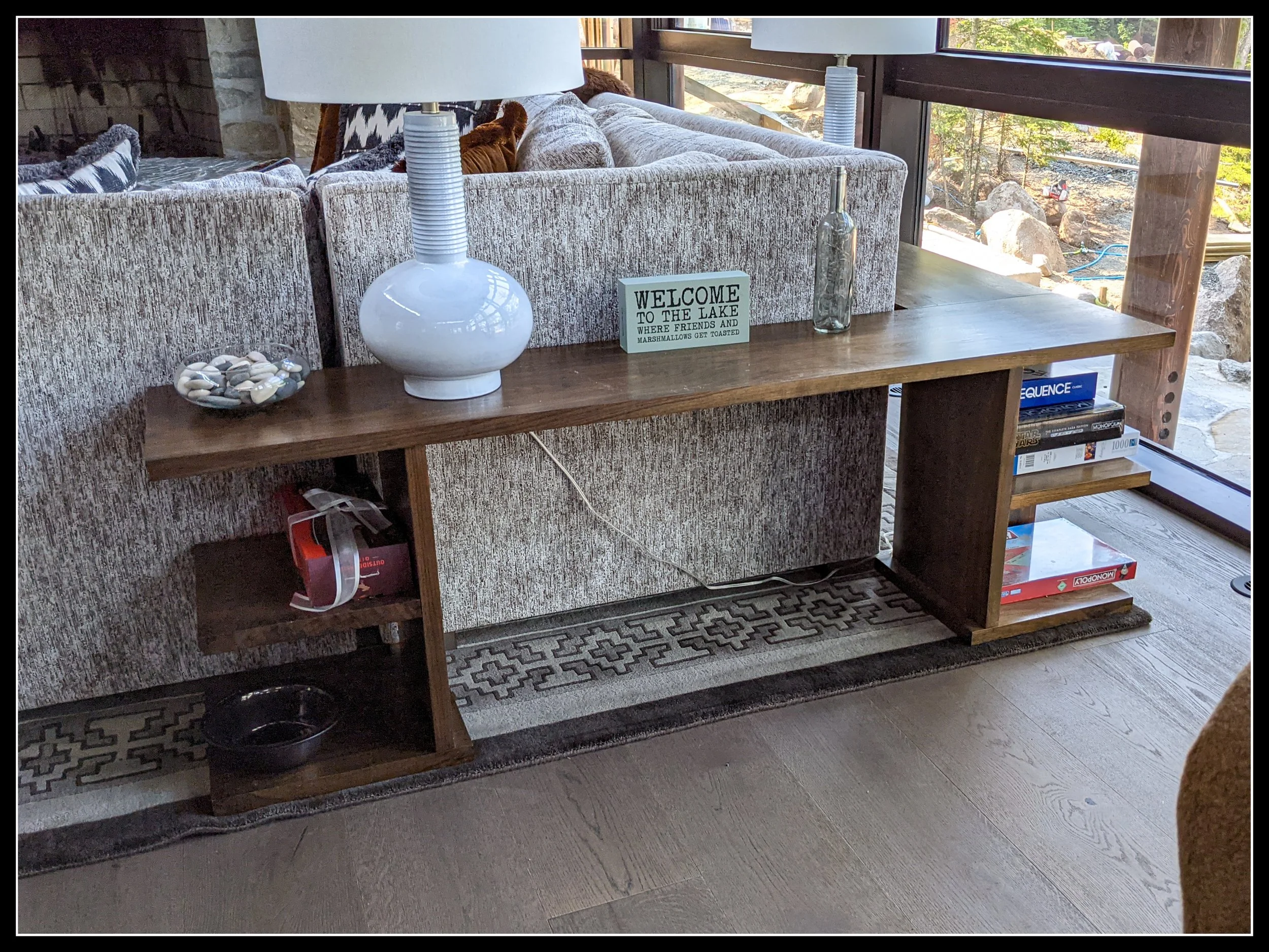Solid walnut wrap‑around sofa table with storage shelves for board games and hardwood grain detail.