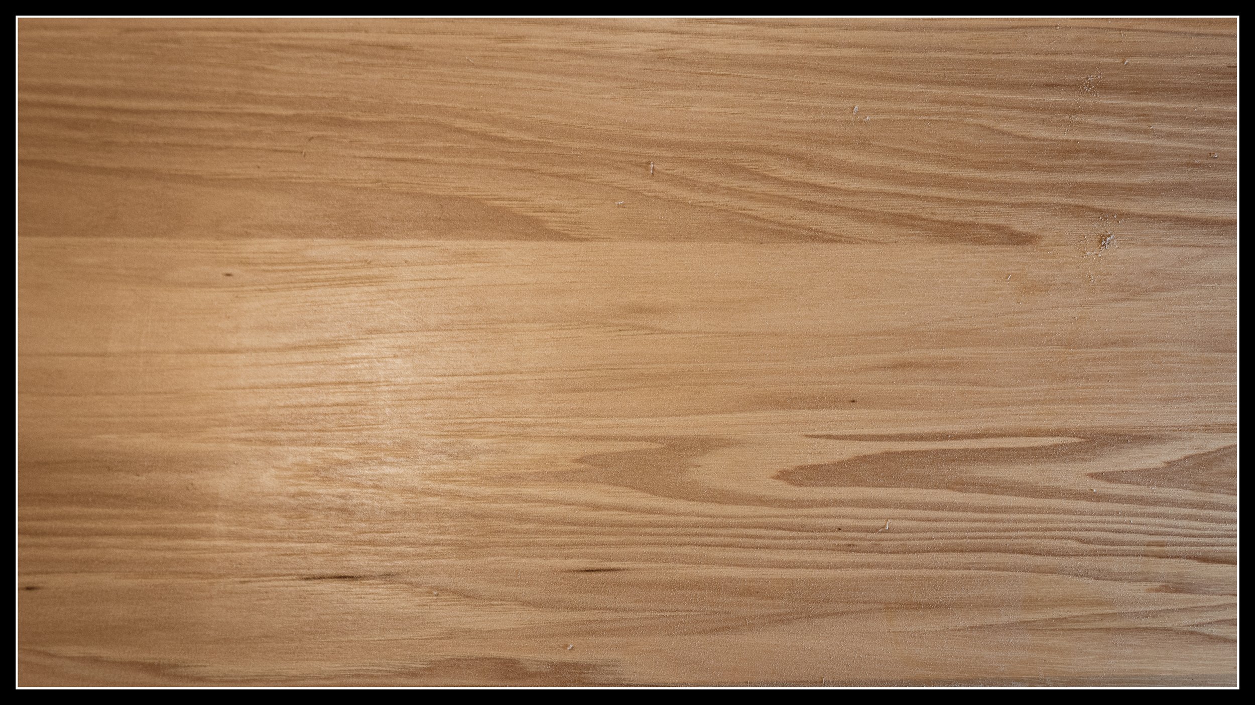 Close‑up photo of hickory wood grain showing dense, fibrous texture with pale sapwood and darker streaks, highlighting the rugged pattern hickory is known for.