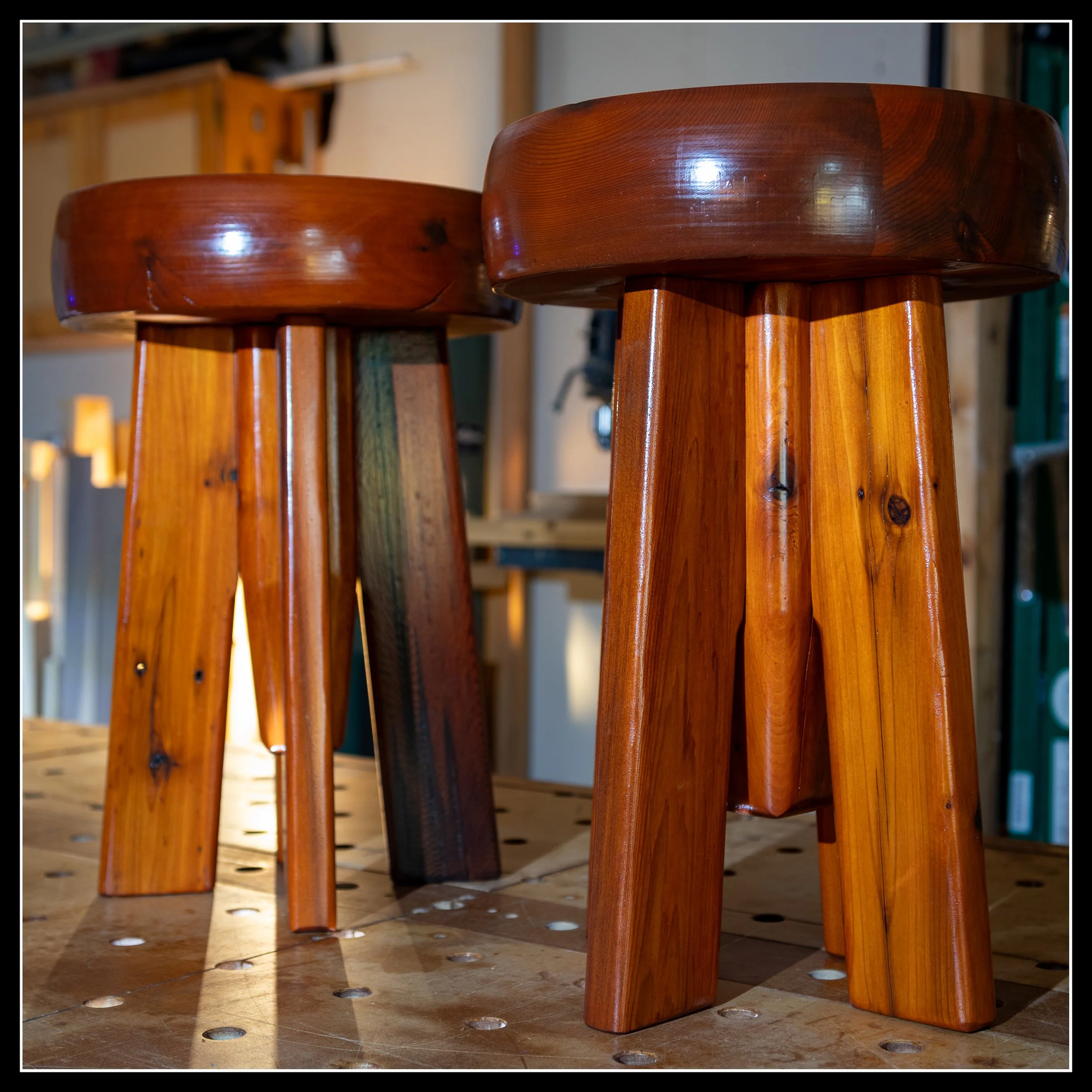 Pair of cedar side tables or stools with thick round tops, finished in a rich long‑oil varnish, showing warm grain, clean shaping, and shop‑built craftsmanship.