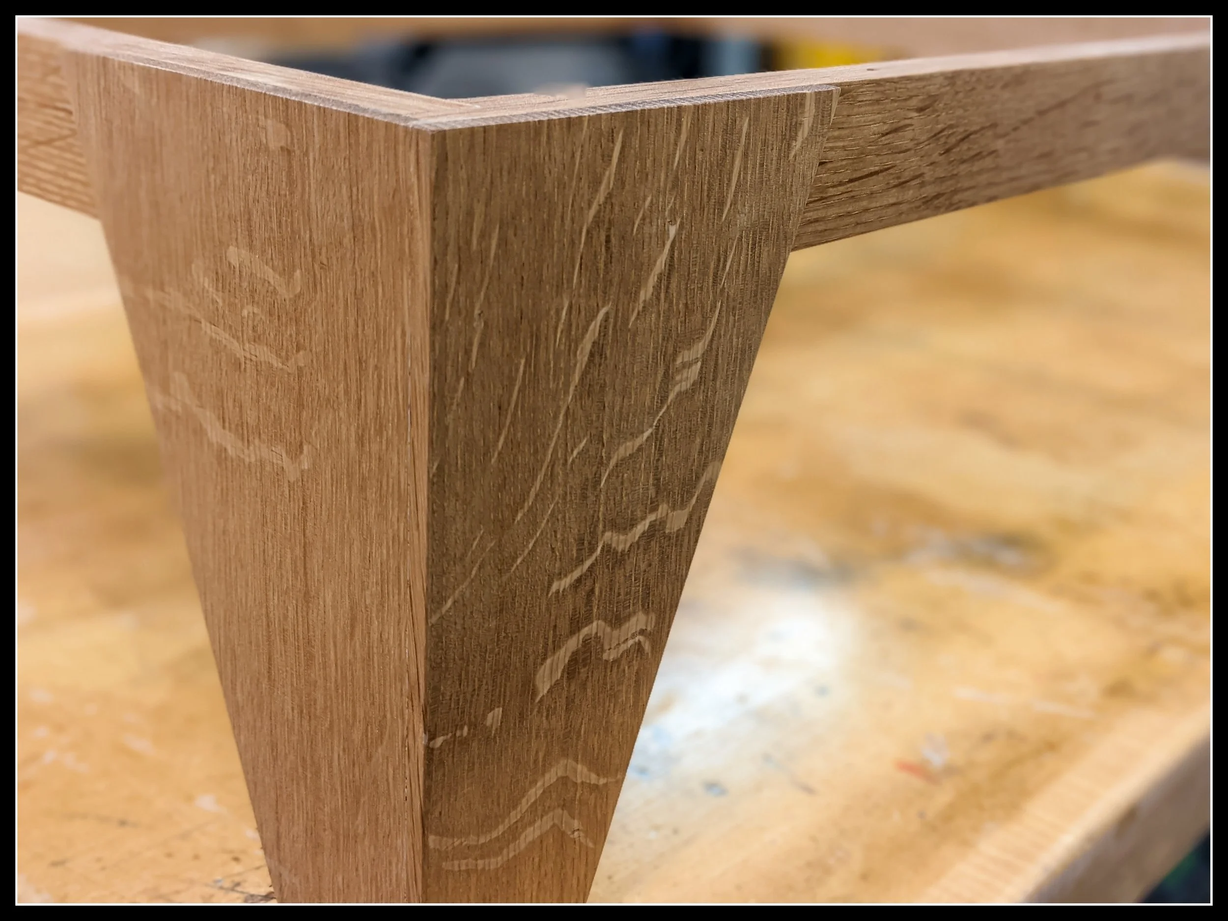 Close up of a solid white oak plinth base with a  crisp mitered corned, showing pronounced ray fleck figure, tight grain structure, and the reflective medullary rays that distinguish quarter-sawn white oak from red oak.