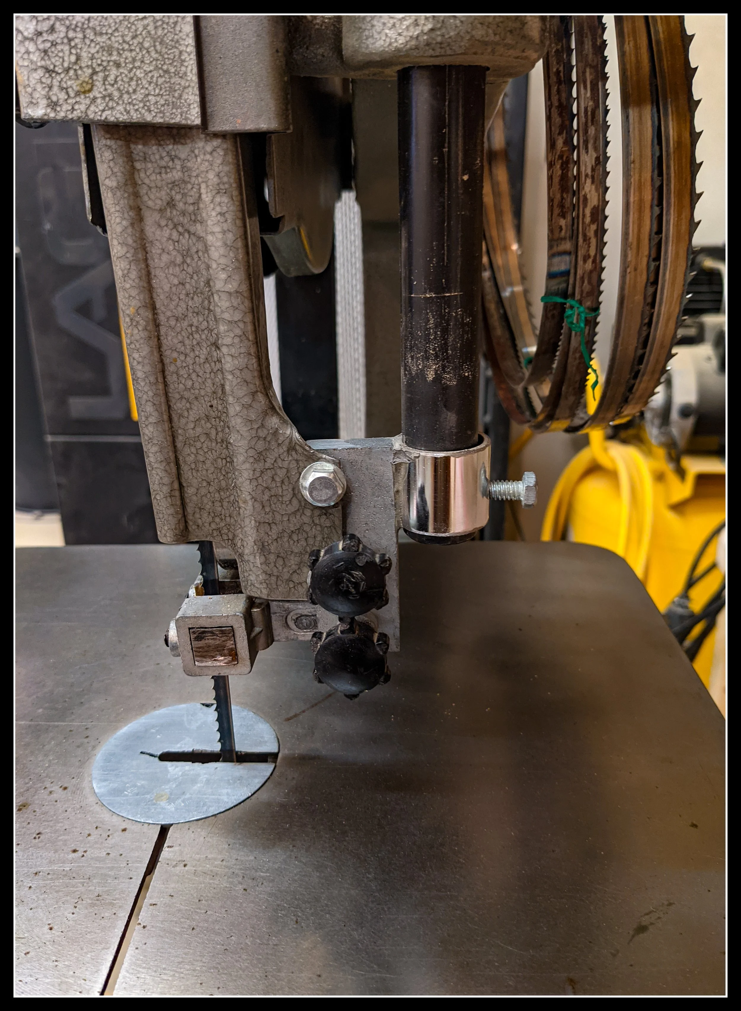 Close-up of a repaired Foremost 14-inch bandsaw guide assembly, showing a closet-rod and JB Weld fix after the original metal crumbled on a 1980s import saw.