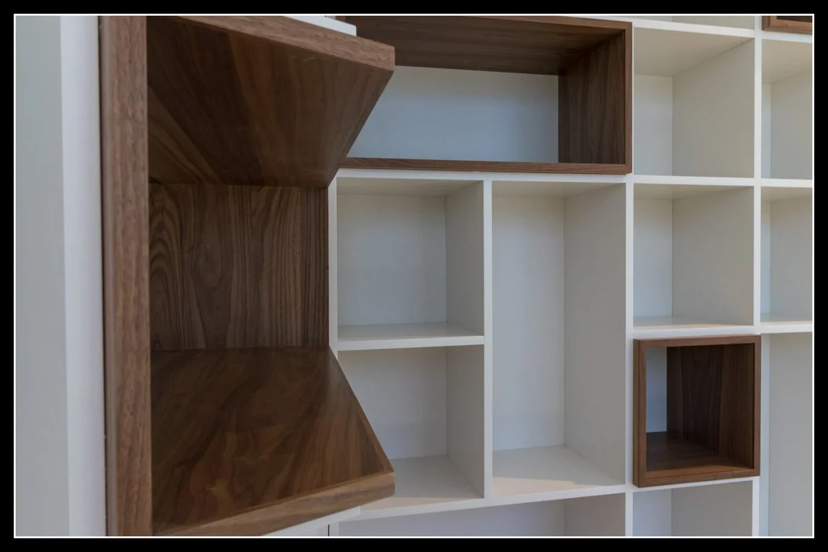 Modern geometric shelving unit with white and wood compartments built over angled walls, showing contrast and asymmetrical design.