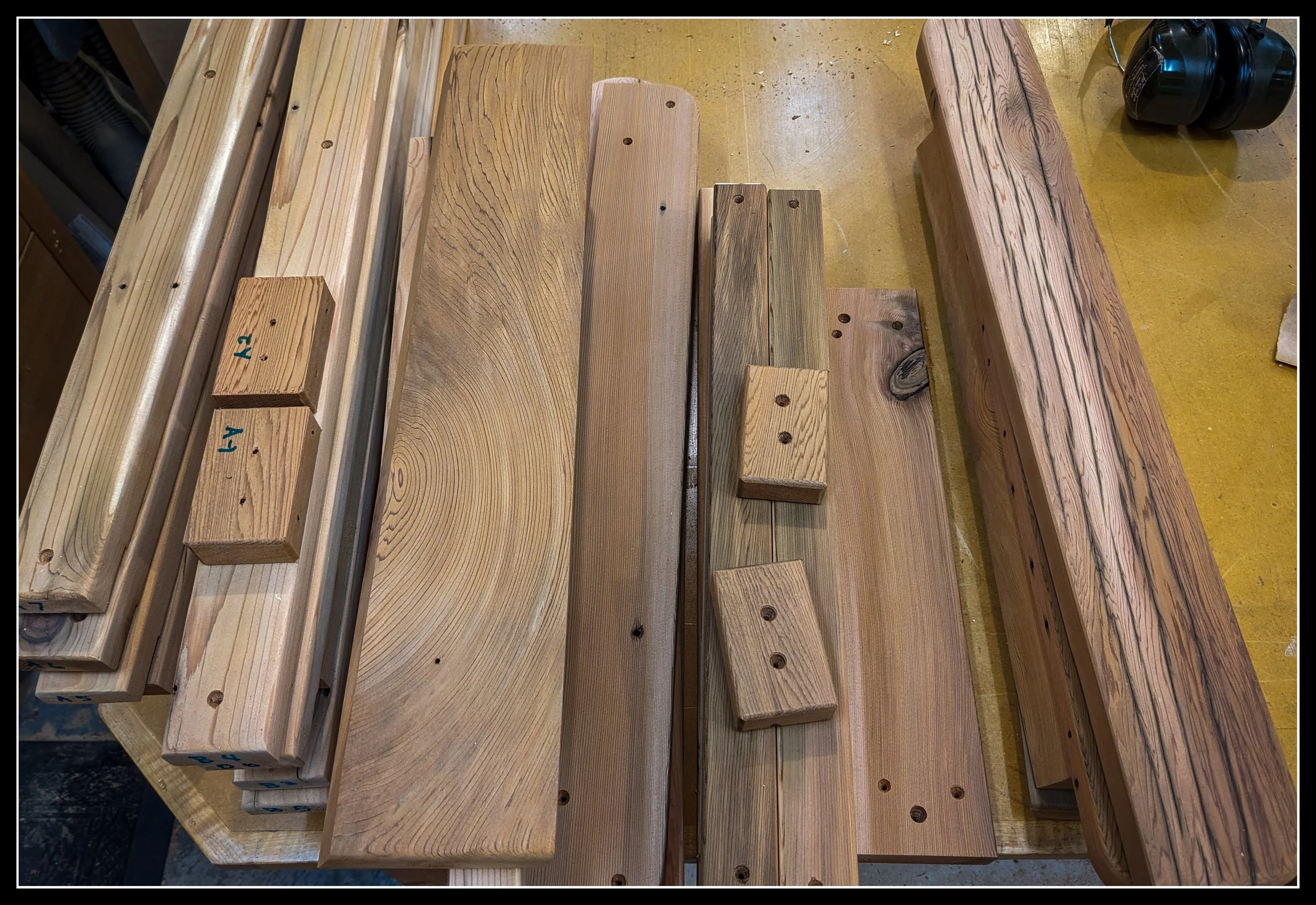 Eastern red cedar boards on a workbench, prepared for Grandpa’s Chair deck‑chair build, showing warm grain and outdoor‑wood stability.