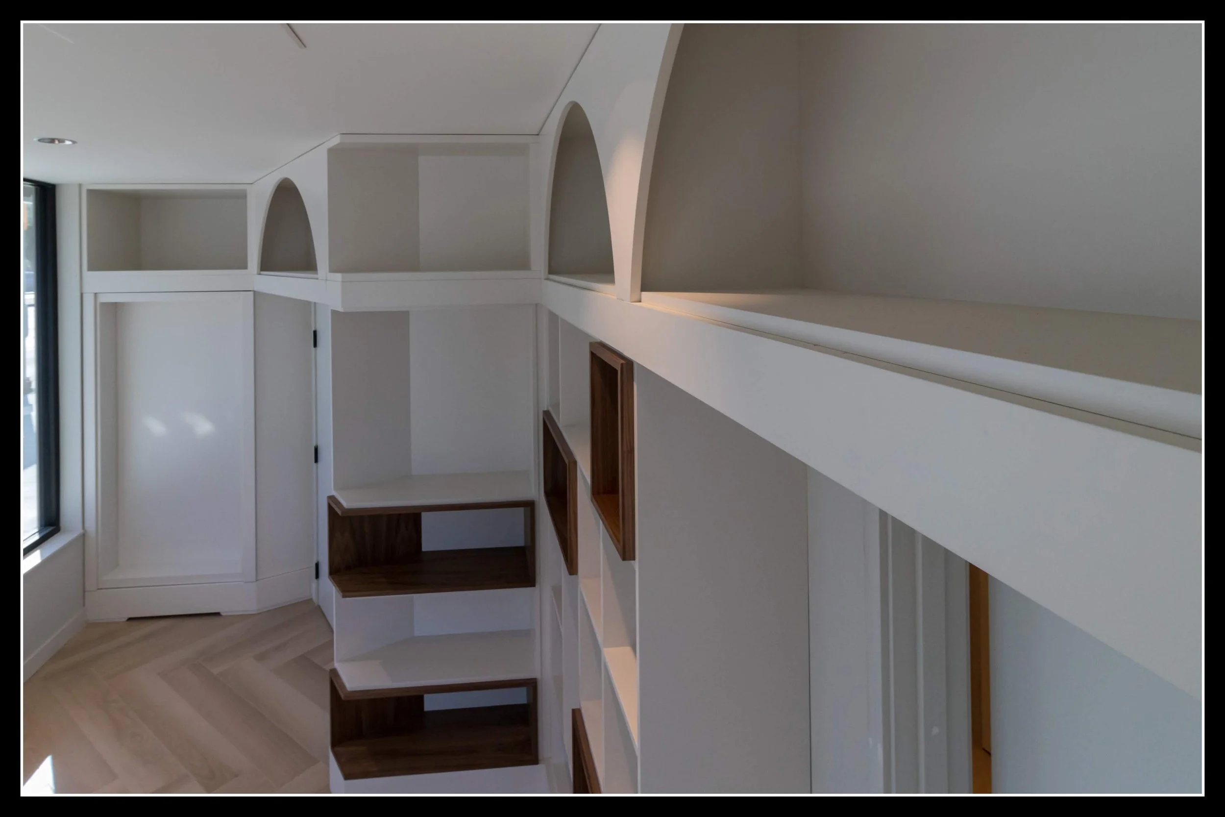 Doctor’s office with custom built‑in cabinetry, arched and rectangular compartments, white architectural panels, and modern integrated storage.