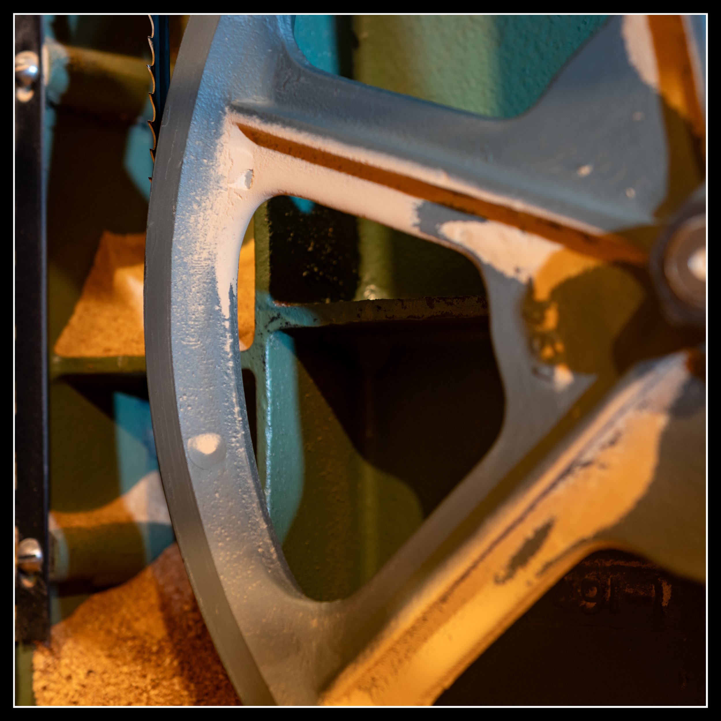 Close-up of the General 490 15-inch Canadian-made bandsaw showing its thick cast‑iron frame and wheel assembly, highlighting the heavy construction that keeps the saw stable and accurate in a woodworking shop.