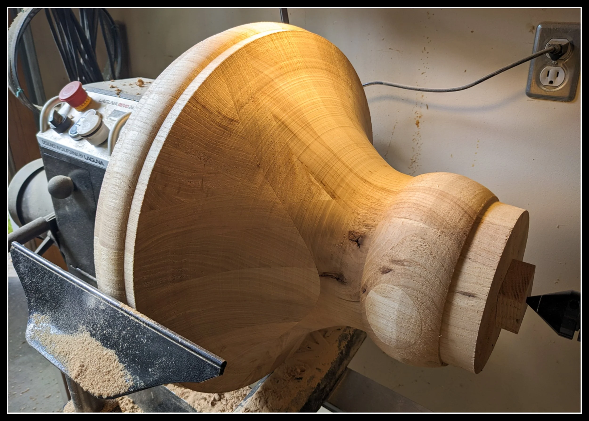 Elm pedestal for a games table being turned on a lathe, shaped in two parts with smooth hardwood curves.