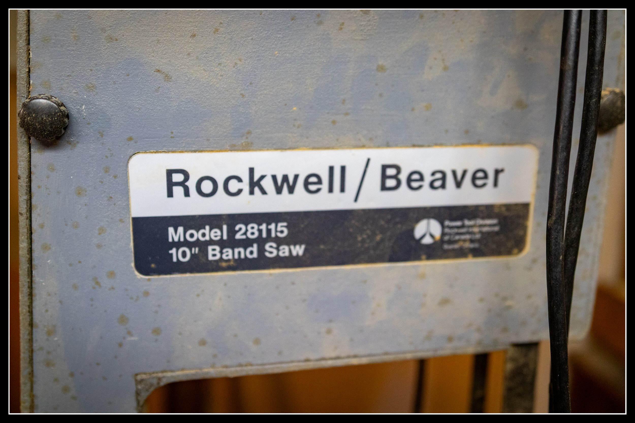 Rockwell/Beaver Model 28115 10-inch bandsaw name plate from the 1950s, showing original branding and cast‑iron machine surface.
