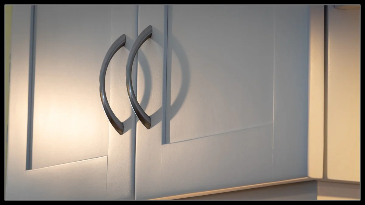 Close-up of gray kitchen cabinet doors with curved metal handles