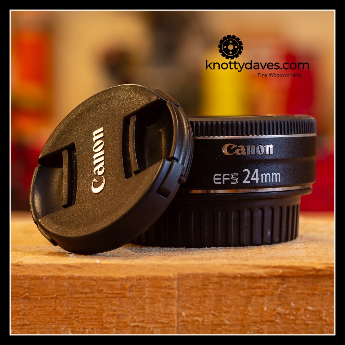 Canon 24mm lens sitting on a wooden surface in the shop, representing the digital side of the workflow where photography documents the craft after the sawdust settles.