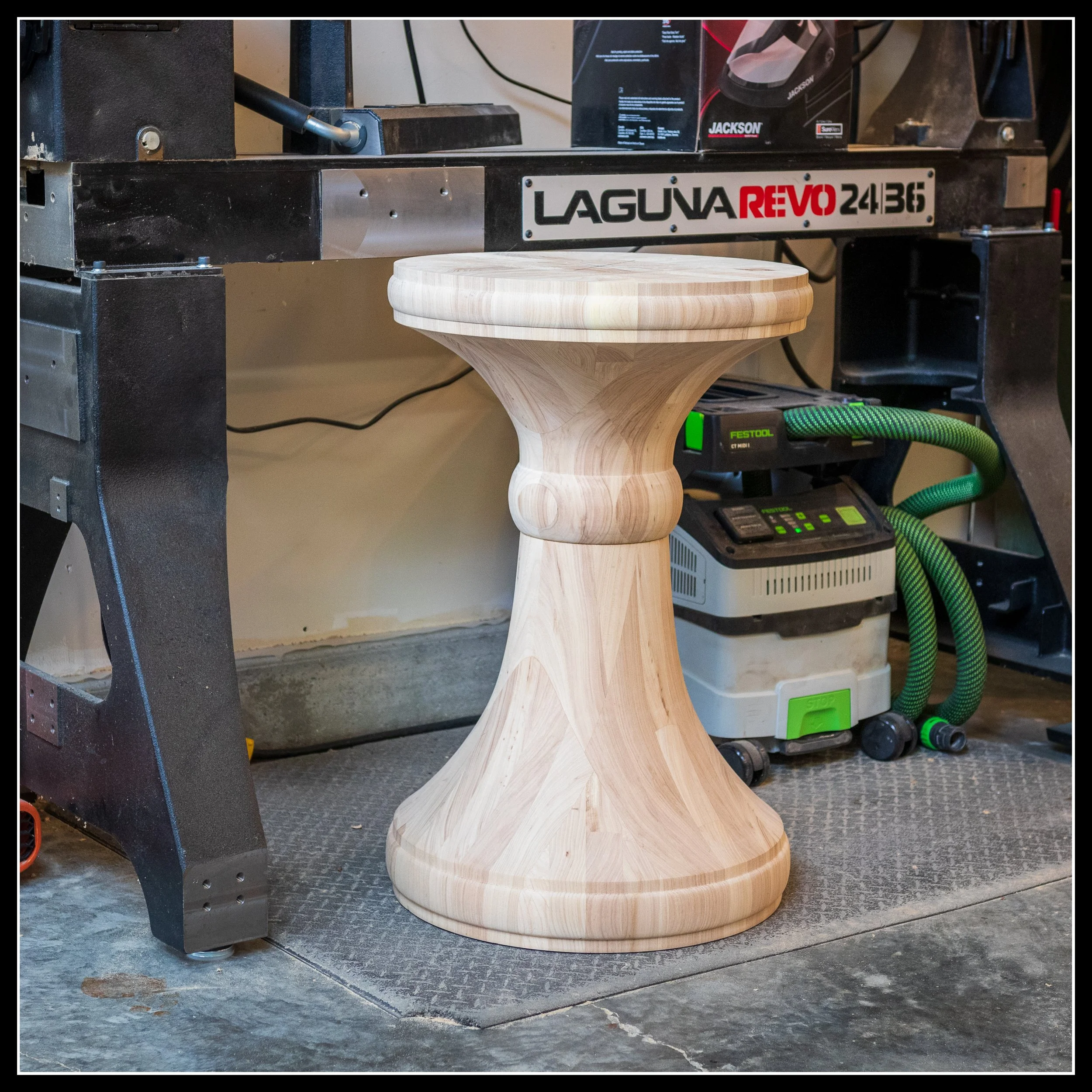 Finished wooden table pedestal in a workshop, turned on a Laguna Revo 24|36 lathe, showing smooth curves, balanced proportions, and professional woodturning craftsmanship.