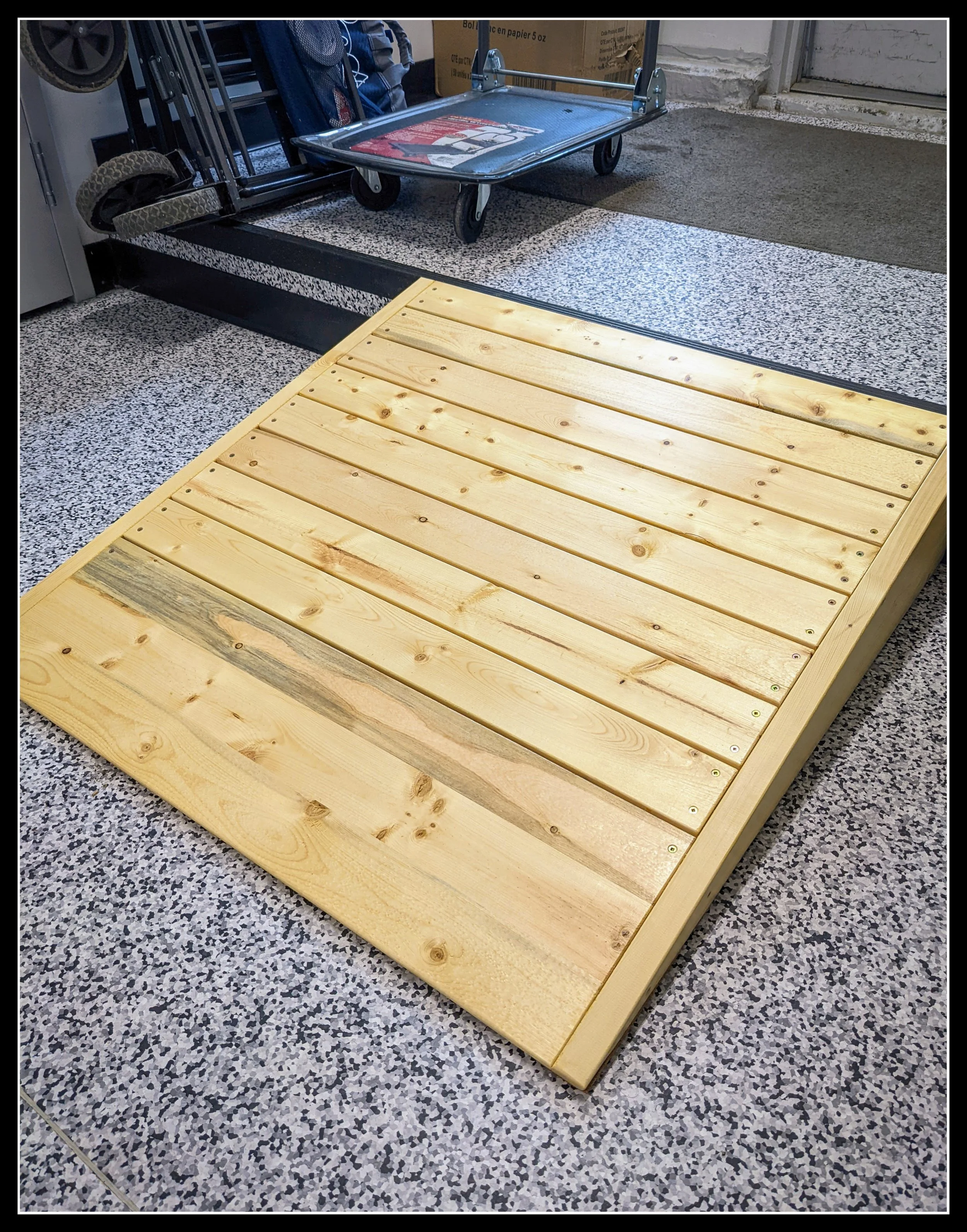 Solid spruce ramp built for a commercial kitchen, showing smooth planks and angled sides for wheeling carts up a step.