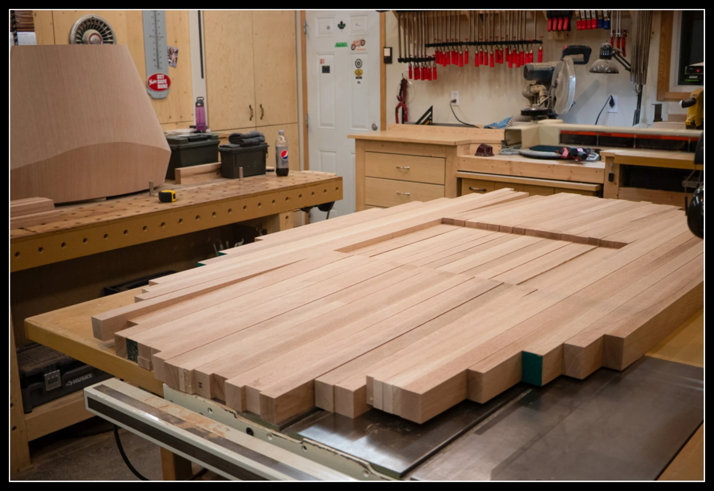 Rough construction stage of an oval red oak table with freshly milled boards arranged on a workbench before glue‑up and shaping.