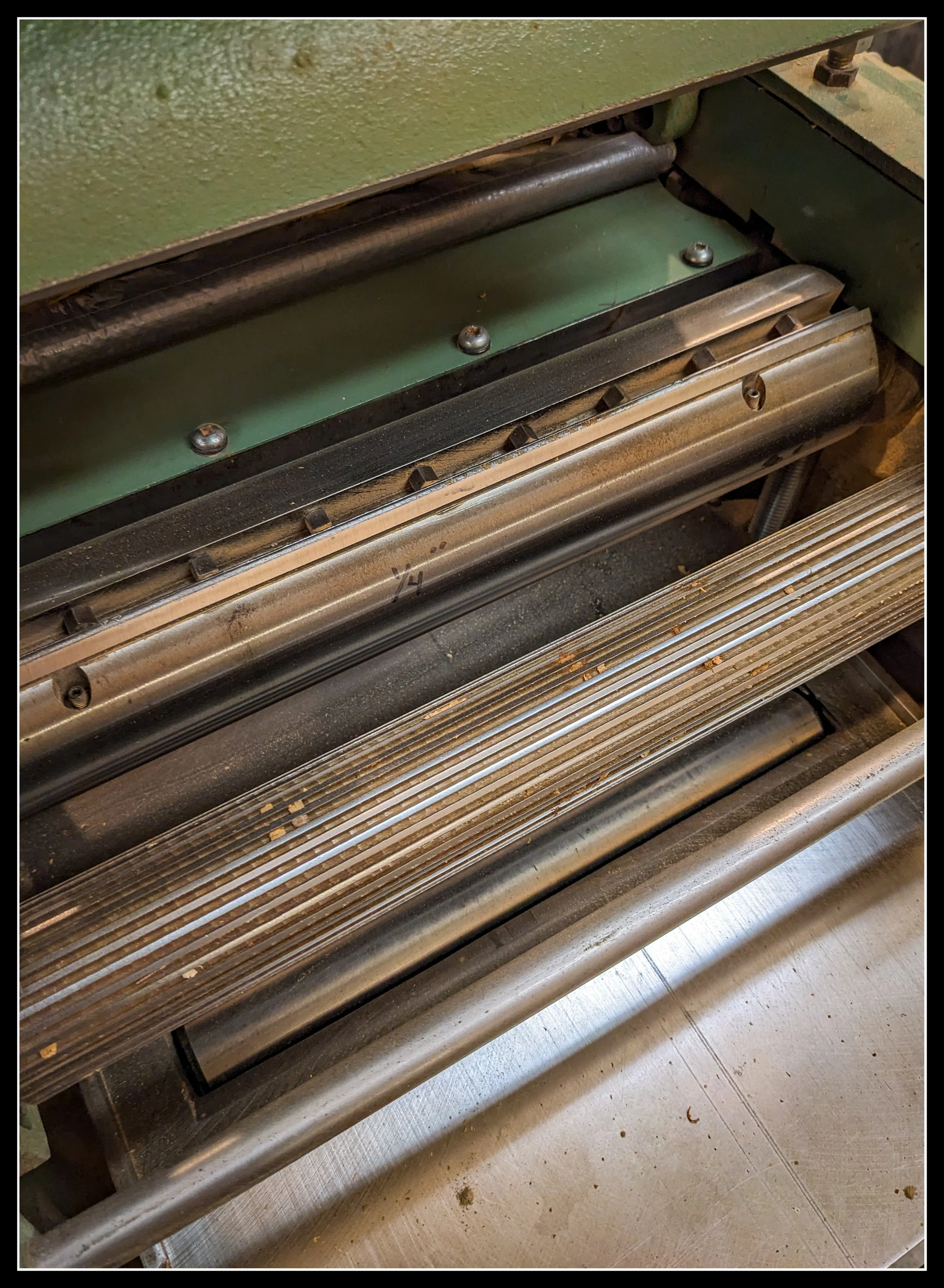Close-up view inside a General 130 thickness planer showing the cutterhead, feed roller, and machined steel components.