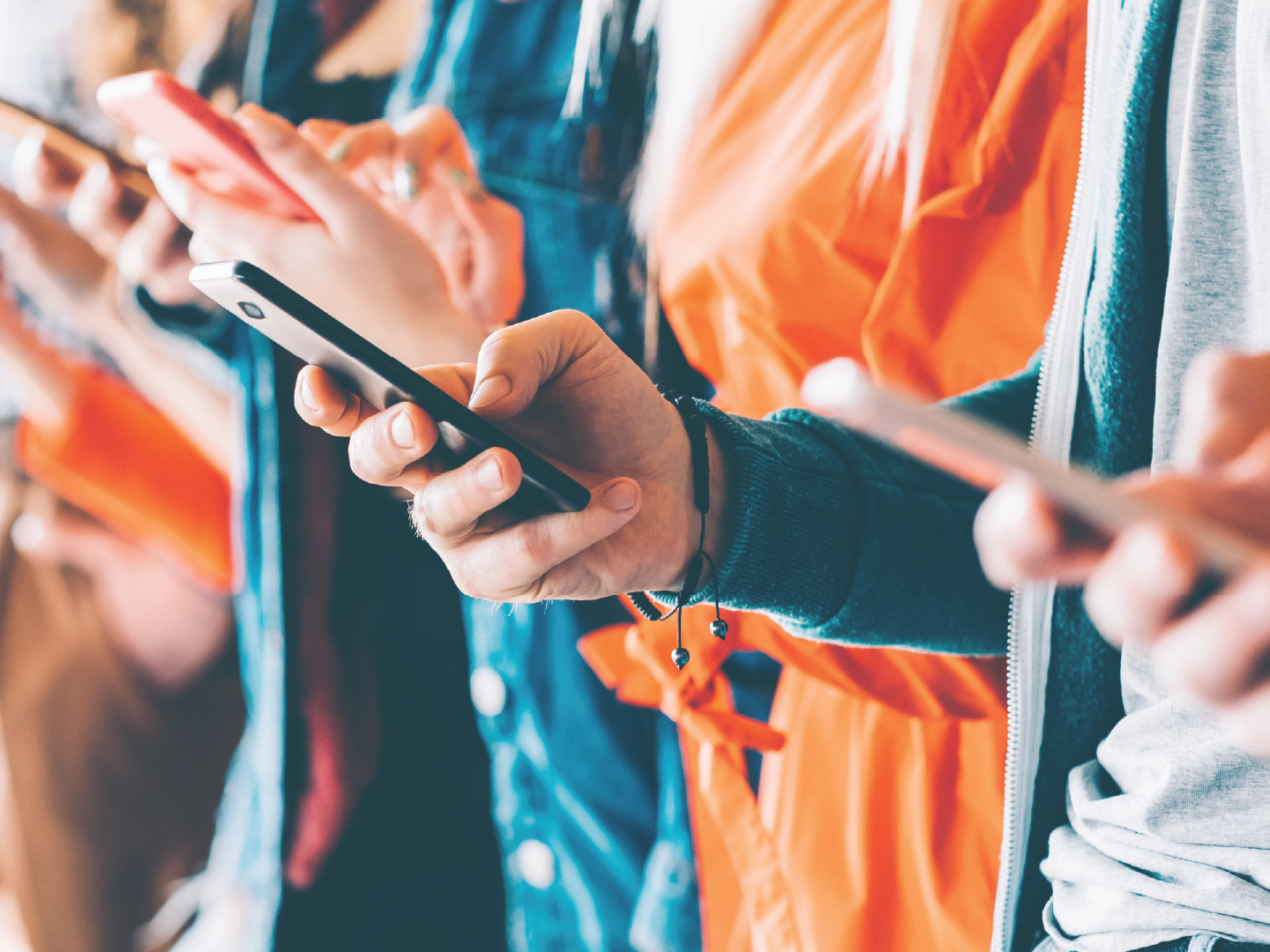 People standing in line, holding smartphones, wearing casual jackets.
