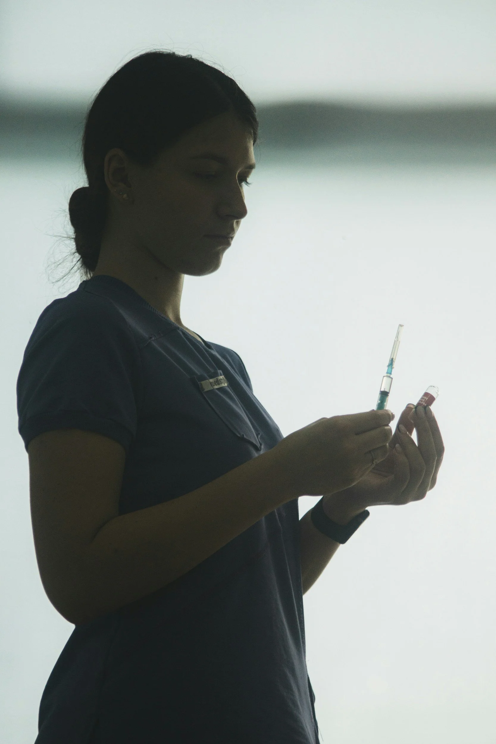 A nurse prepares a syringe with a vaccine or medication.