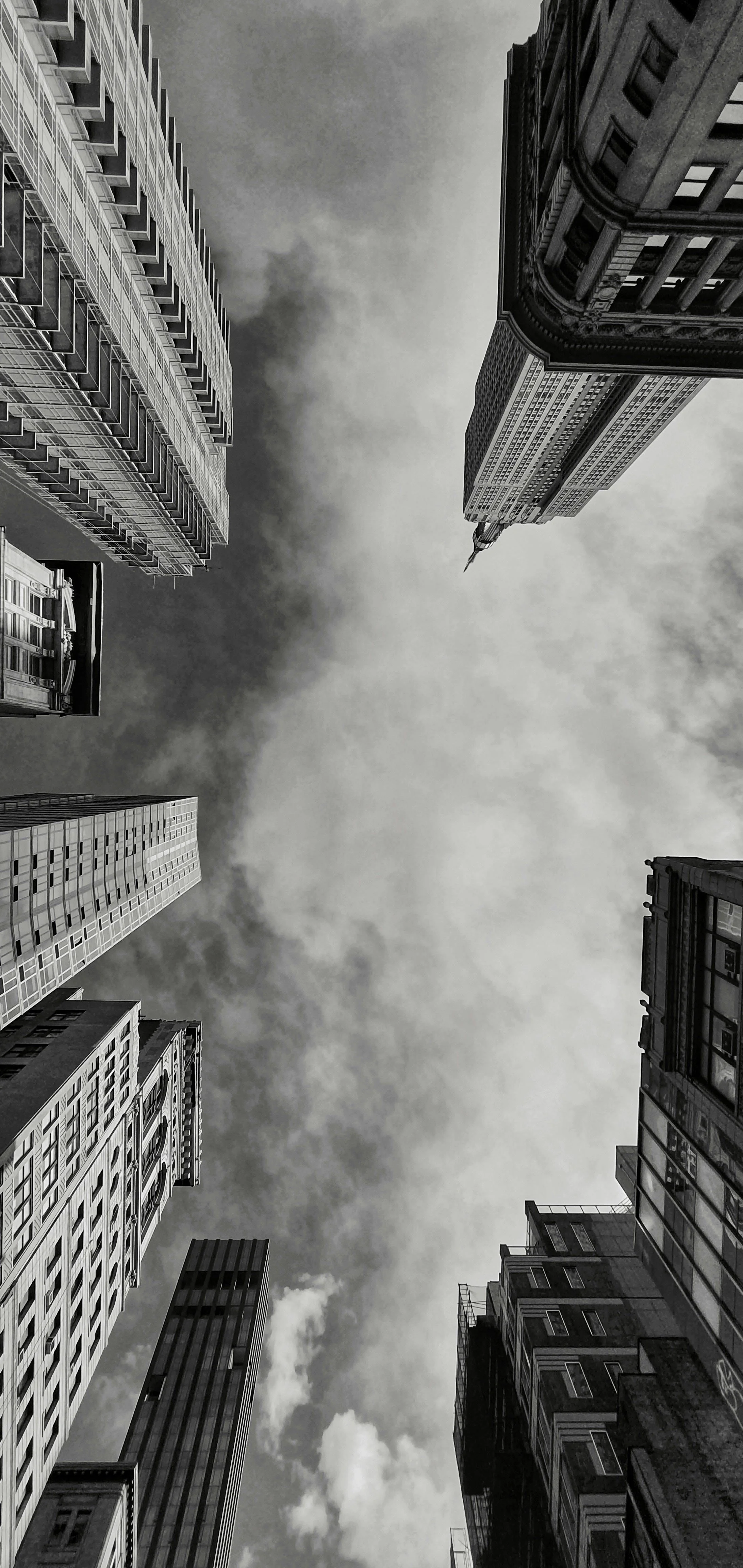 Looking up at tall skyscrapers in a city with cloudy sky.