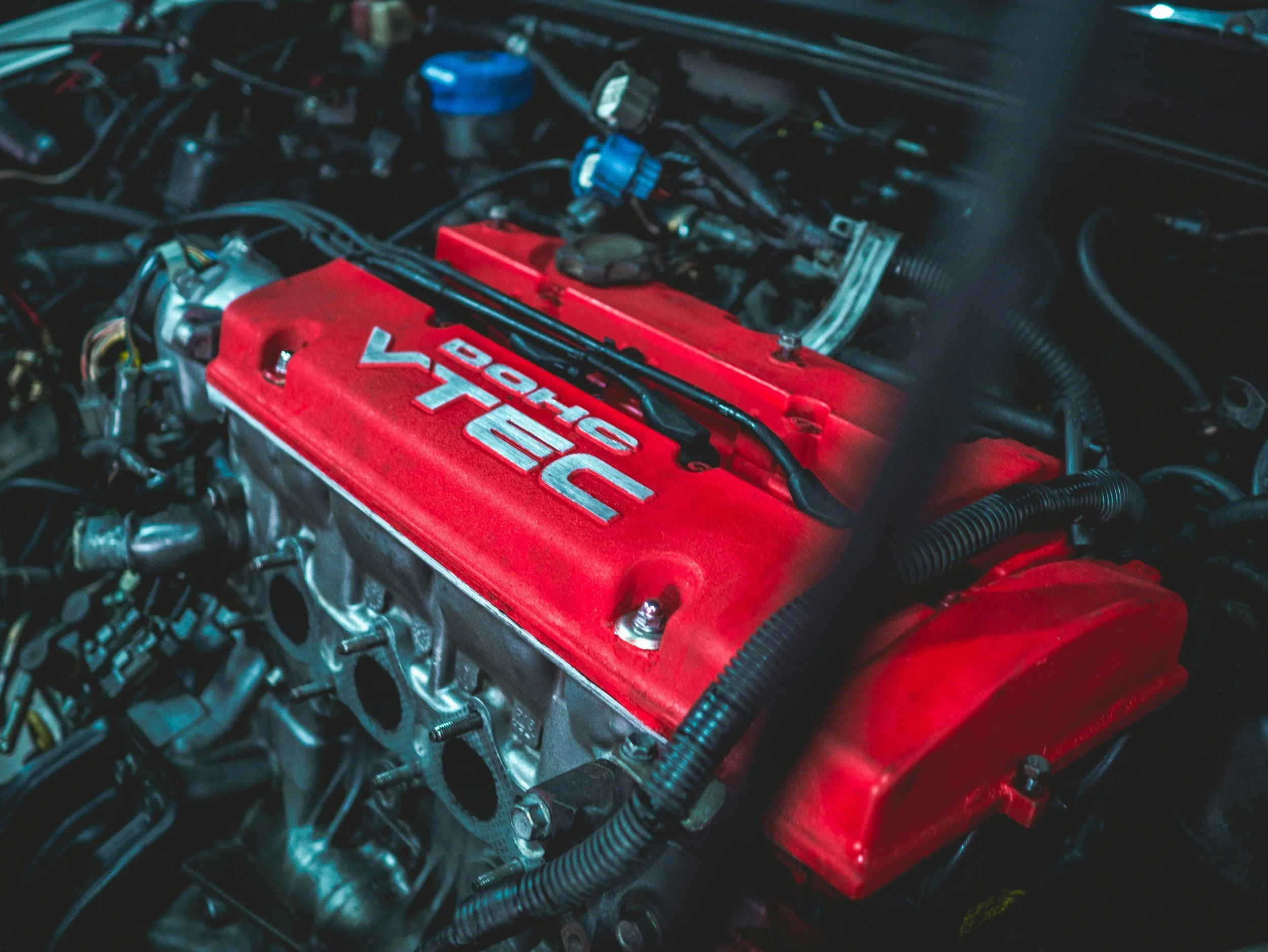 Close-up of a red Honda D16VTEC engine inside a car engine bay.