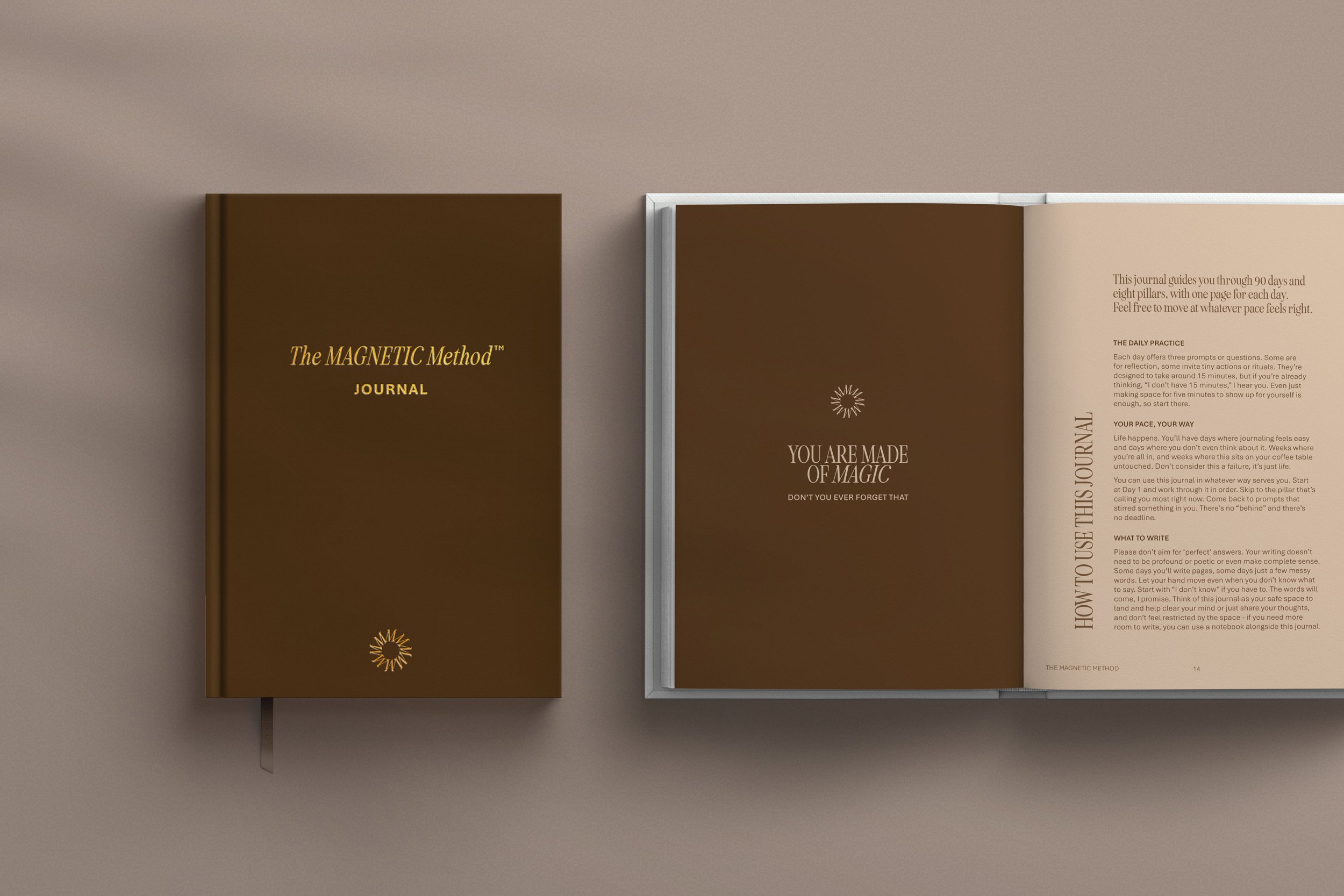 Open journal with a brown cover titled 'The MAGNETIC Method JOURNAL' with a sun logo at the bottom, next to a closed brown journal titled 'YOU ARE MADE OF MAGIC' with a sun logo, both placed on a beige surface.