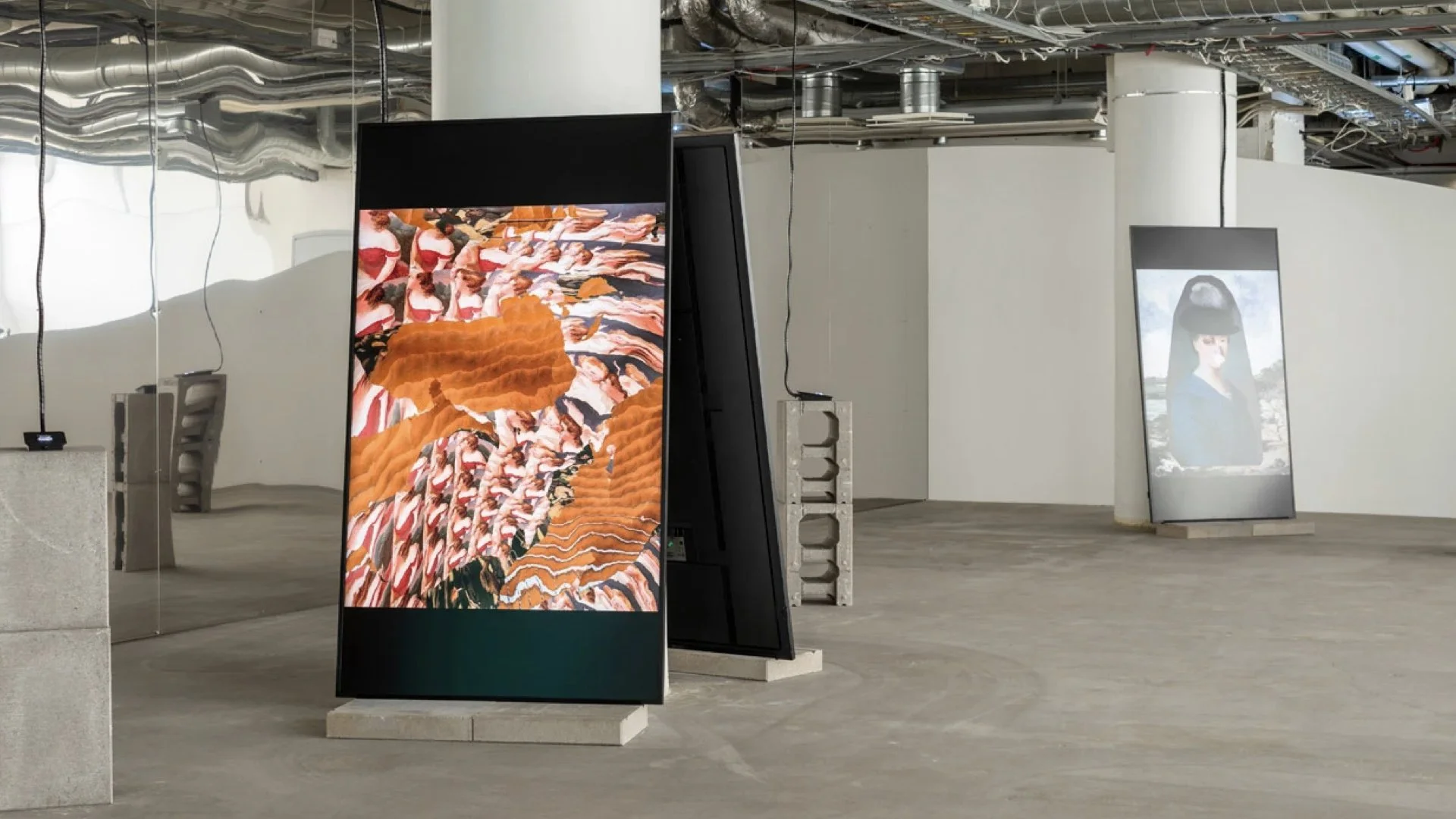 Finnish National Gallery, Remix the Archive. Two digital display screens showing vibrant images, set in an unfinished industrial-like space with exposed pipes and ductwork.