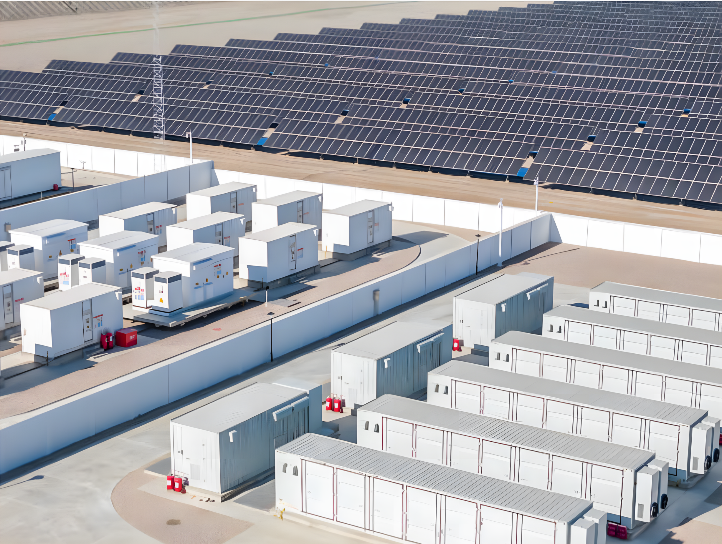 Aerial view of a commercial solar power installation featuring solar panels on the roof and white modular structures on the ground, with a clear sky and some electrical equipment.