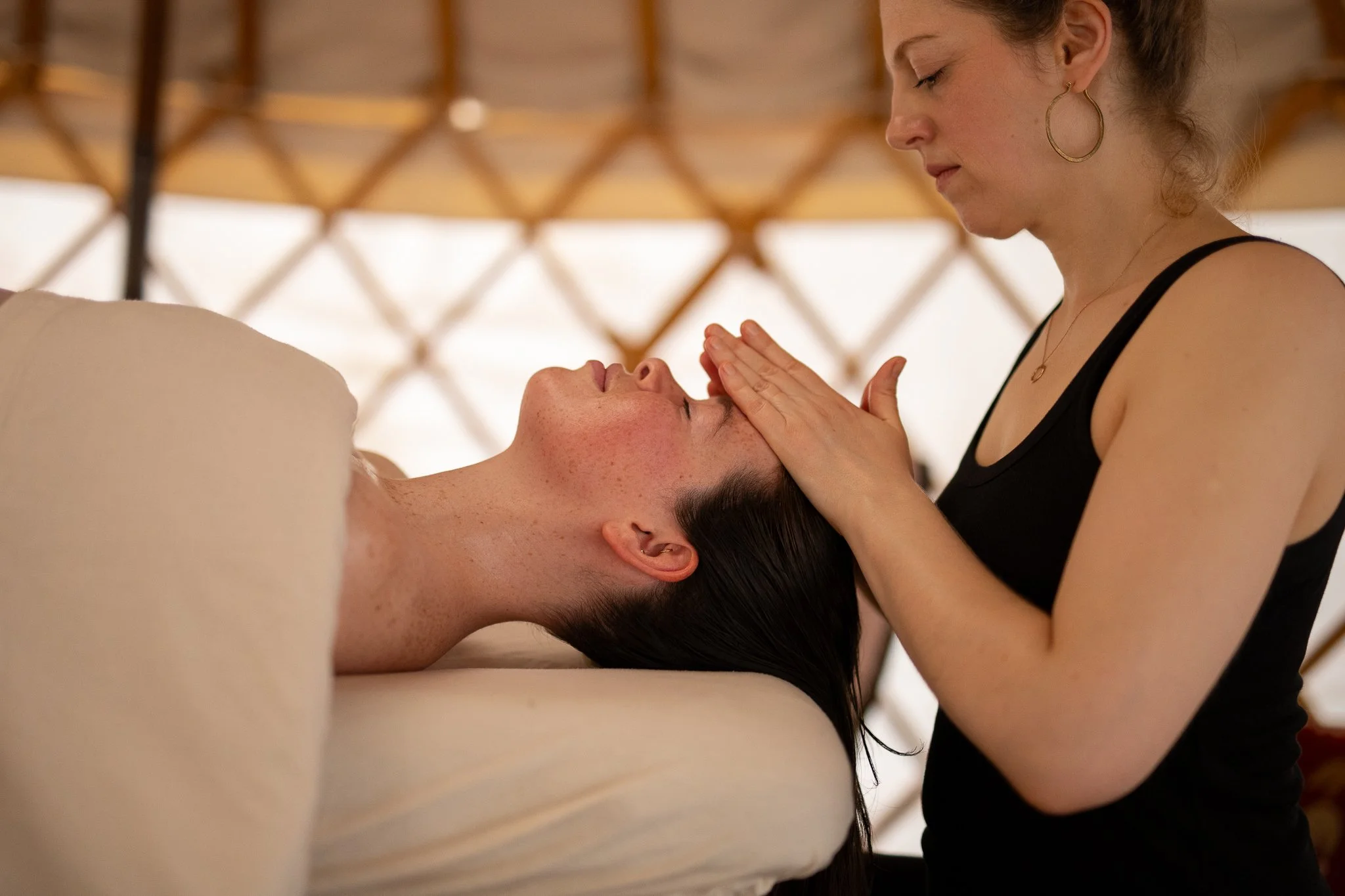 A woman receiving a facial treatment from a practitioner in a spa or wellness center.