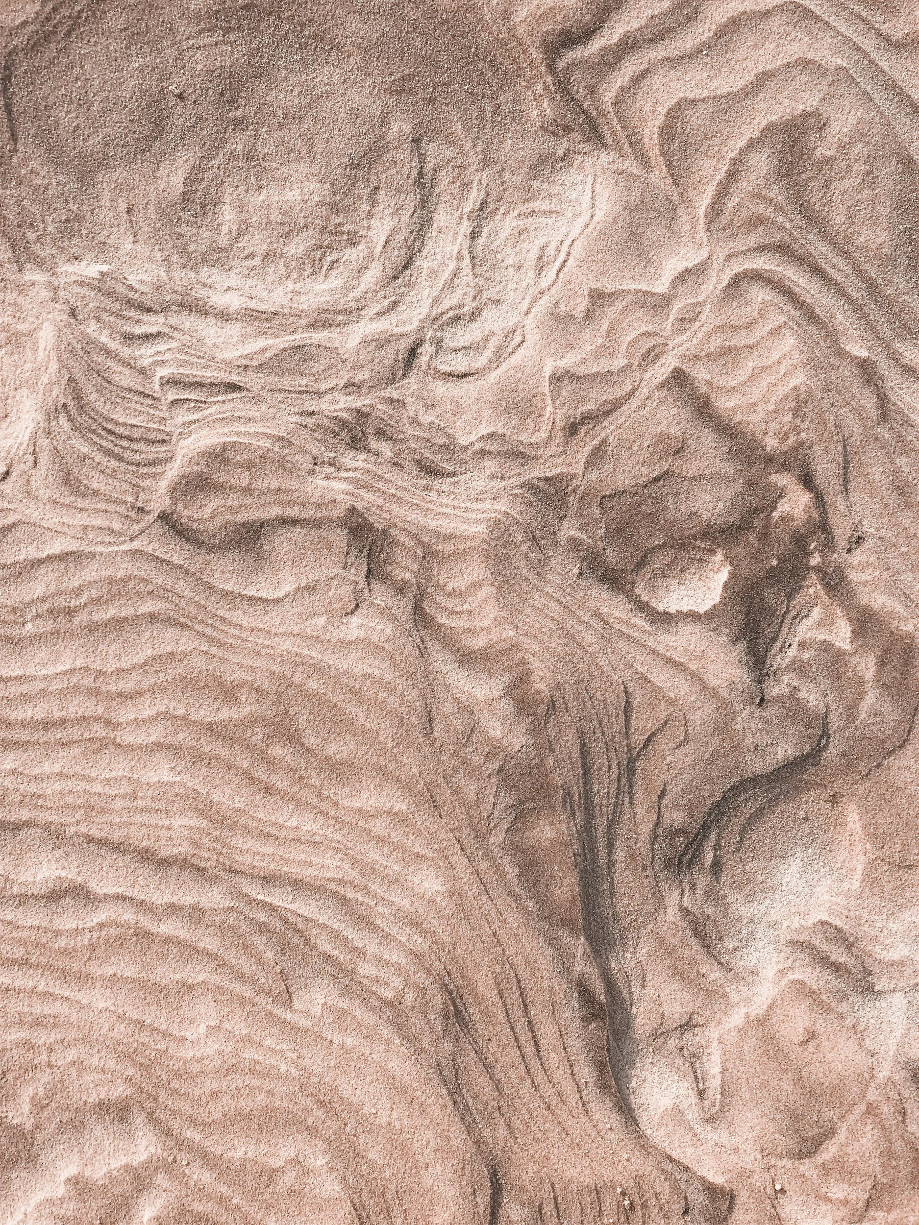 Close-up of sand with natural ripple and wave patterns.