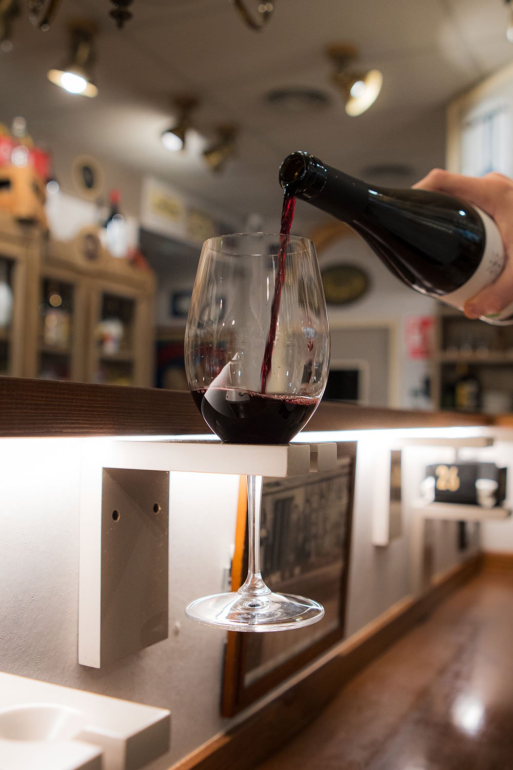 Persona sirviendo vino tinto en una copa en un bar o restaurante.