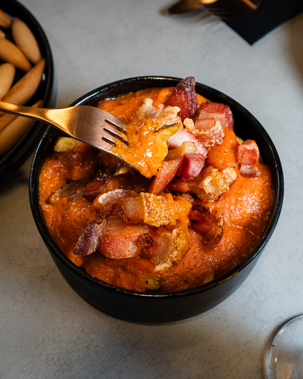 Guiso de patatas y torreznos de Soria en un cuenco negro.