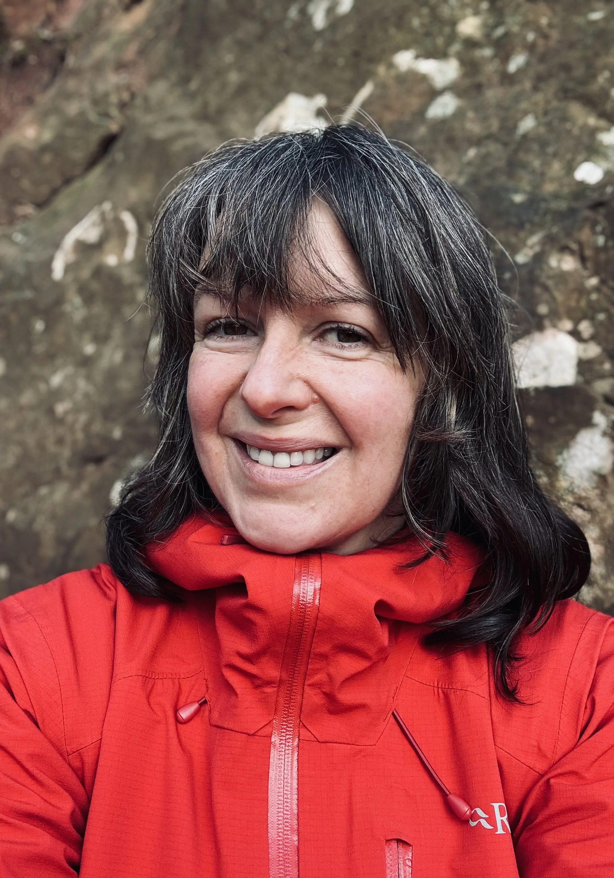 Leigh Bradley, Art Project Director, standing outdoors in front of a stone artwork