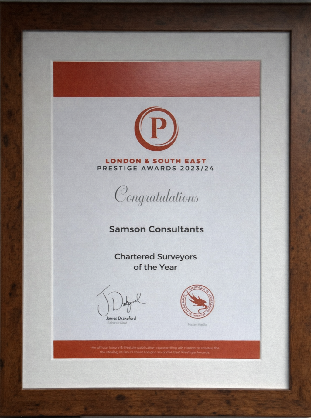 Framed certificate for Samson Consultants, awarded at the London & South East Prestige Awards 2023/24, signed by James Drakeford and Foster Media, with a red logo at the top and a red banner at the bottom.