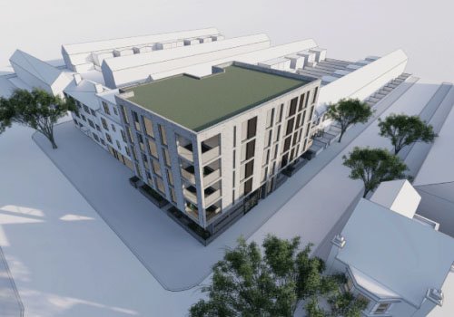 A modern, multi-story building with a green rooftop, surrounded by trees and situated in an urban area.