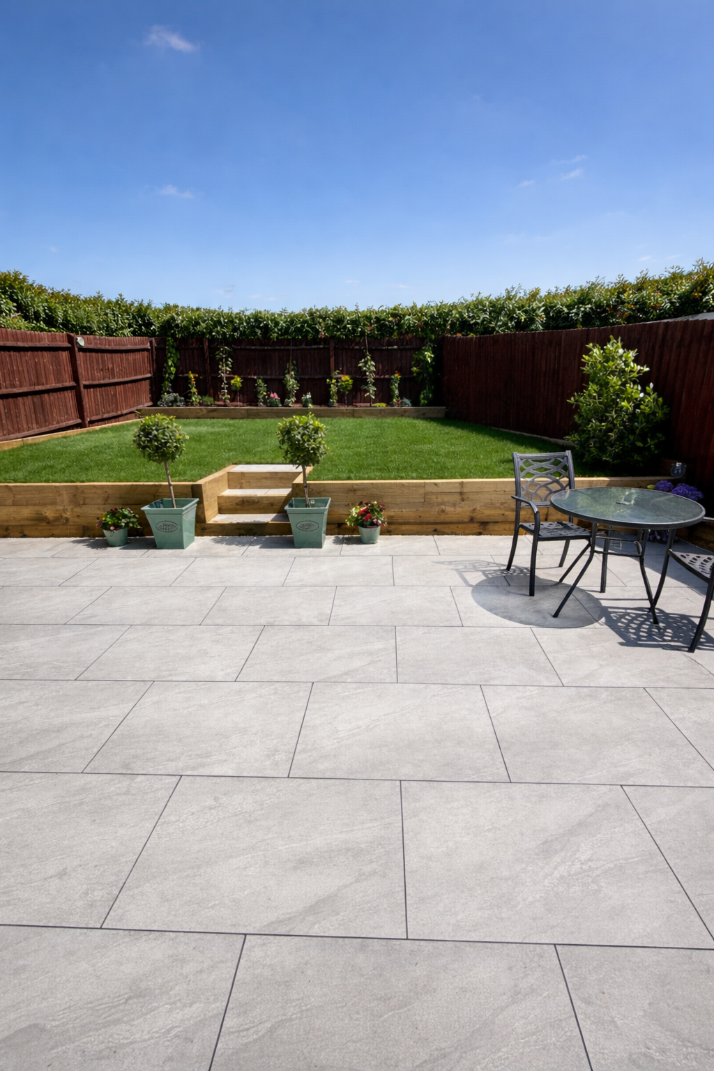 Garden transformation picture showcasing porcelain patio, sleeper retaining walls and steps with fresh turf in Derby