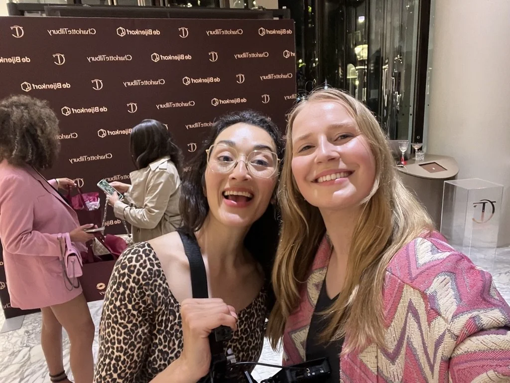 Two women smiling for a selfie at a Charlotte Tilbury event from de Bijenkorf.