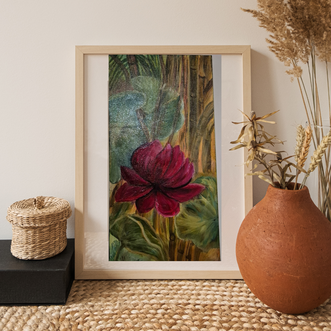 A framed painting of a red flower with green leaves, presented in a natural setting with woven textures and earthy elements that complement the artwork’s organic feel.