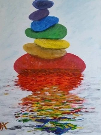 Colorful stones stacked in a pyramid on water, with their reflection visible.