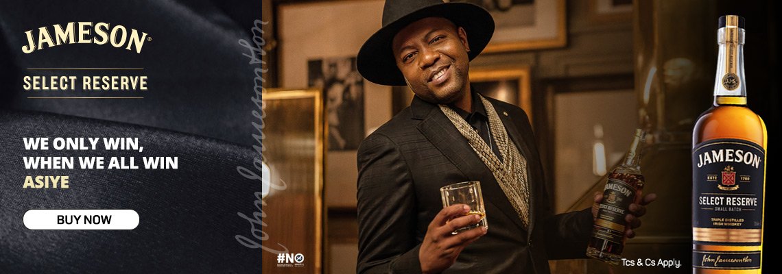 JAMESON AISYE CAMPAIGN
Man dressed in a suit and hat holding a glass of whiskey and a bottle of Jameson Select Reserve whiskey in a bar setting.