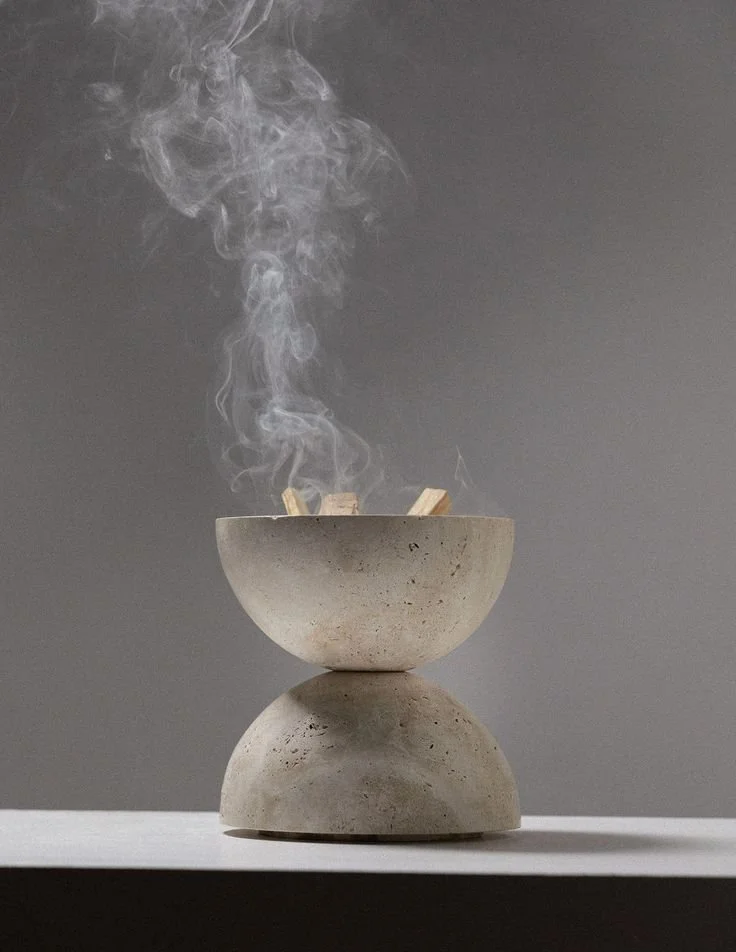A concrete bowl with palo santo burning smoke