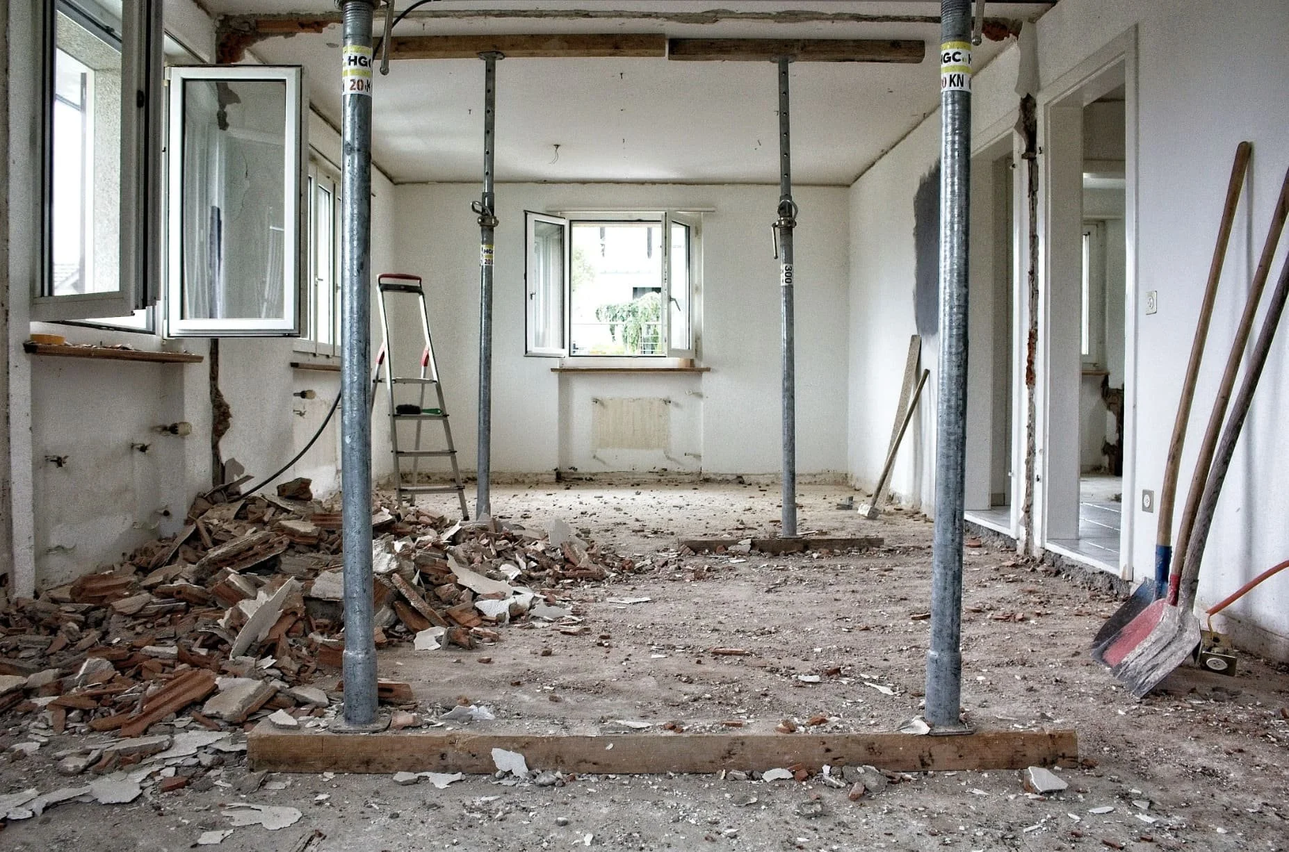 Interior of a room under renovation with debris on the floor and construction supports in place.
