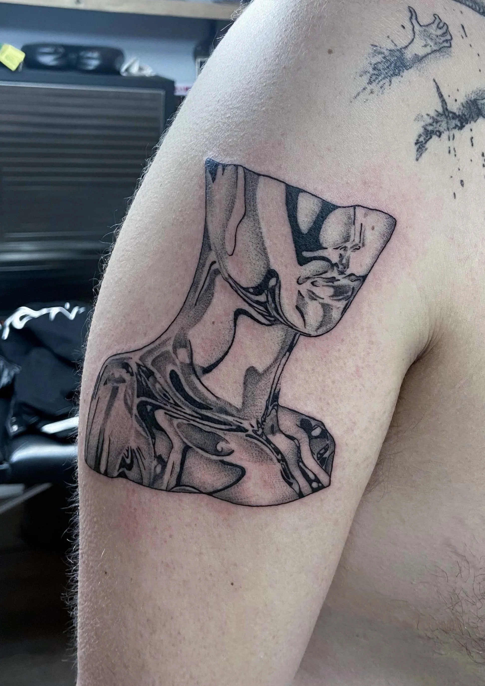 Line art tattoo of an abstract, stylized car part, possibly a face or animal.