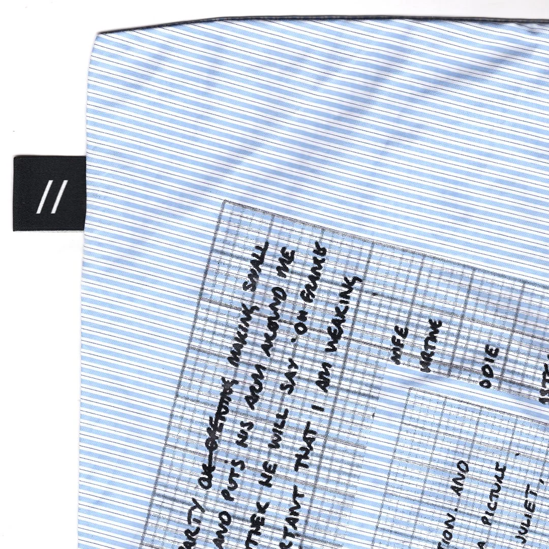 Close-up of a light blue, white, and gray striped fabric with handwritten notes on graph paper overlaid.