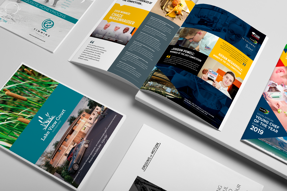 Brochures and booklets laid out on a white surface, featuring content about awards, events, and real estate properties.