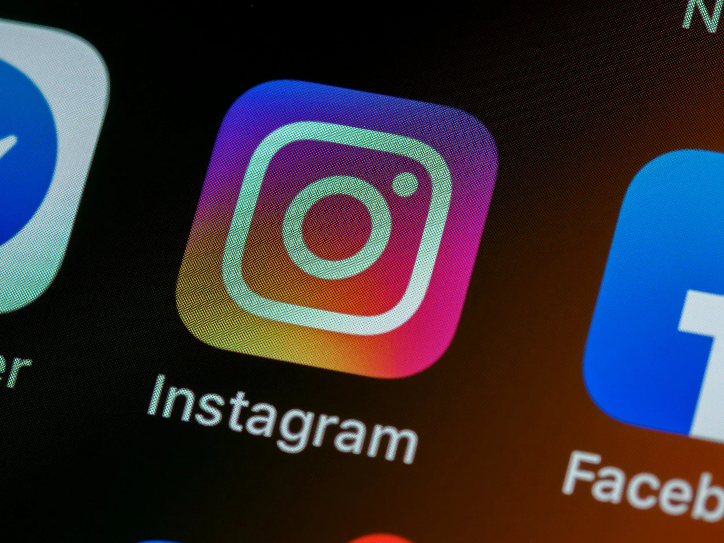 Close-up of a smartphone screen displaying the Instagram app icon, which is a multicolored gradient square with a white outline of a camera.
