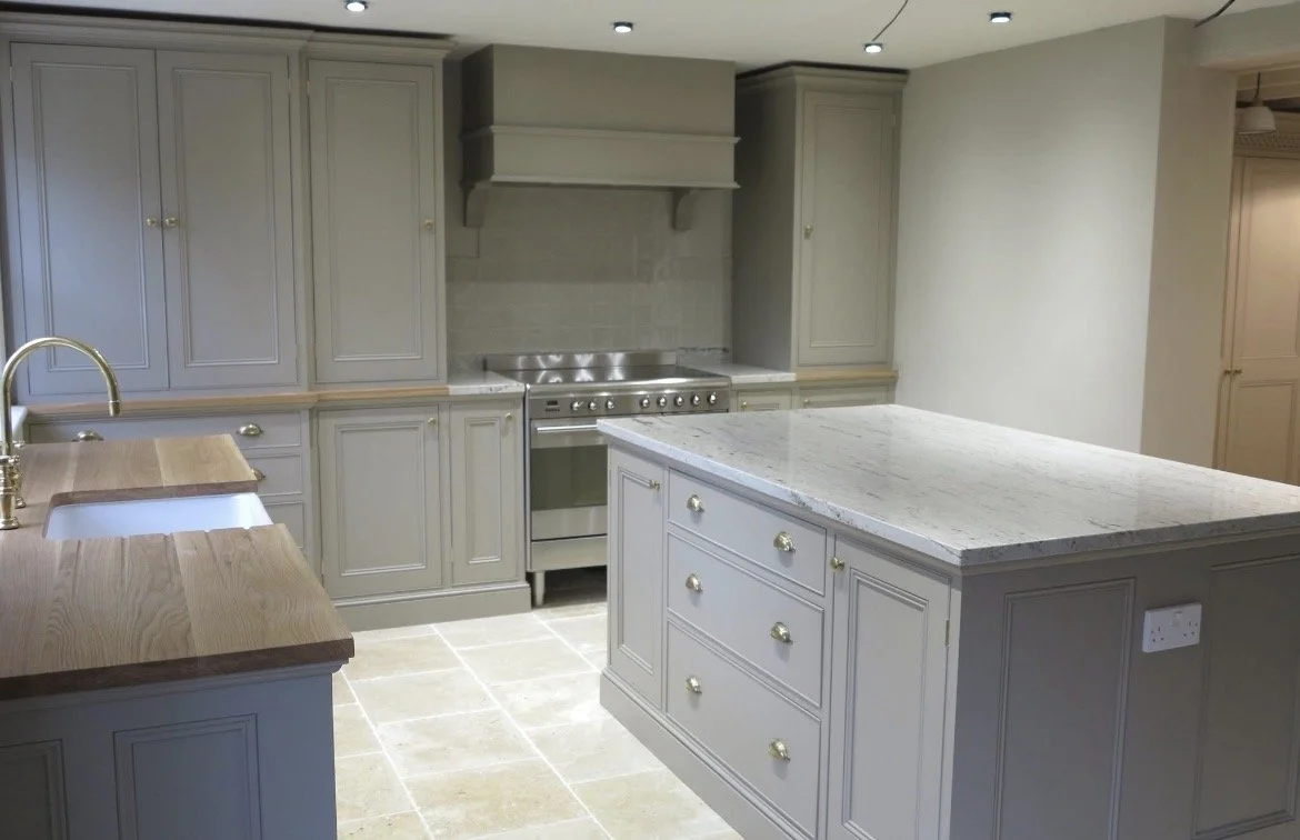 Kitchen with gray cabinets, a marble countertop island, a stainless steel stove, and a double sink.