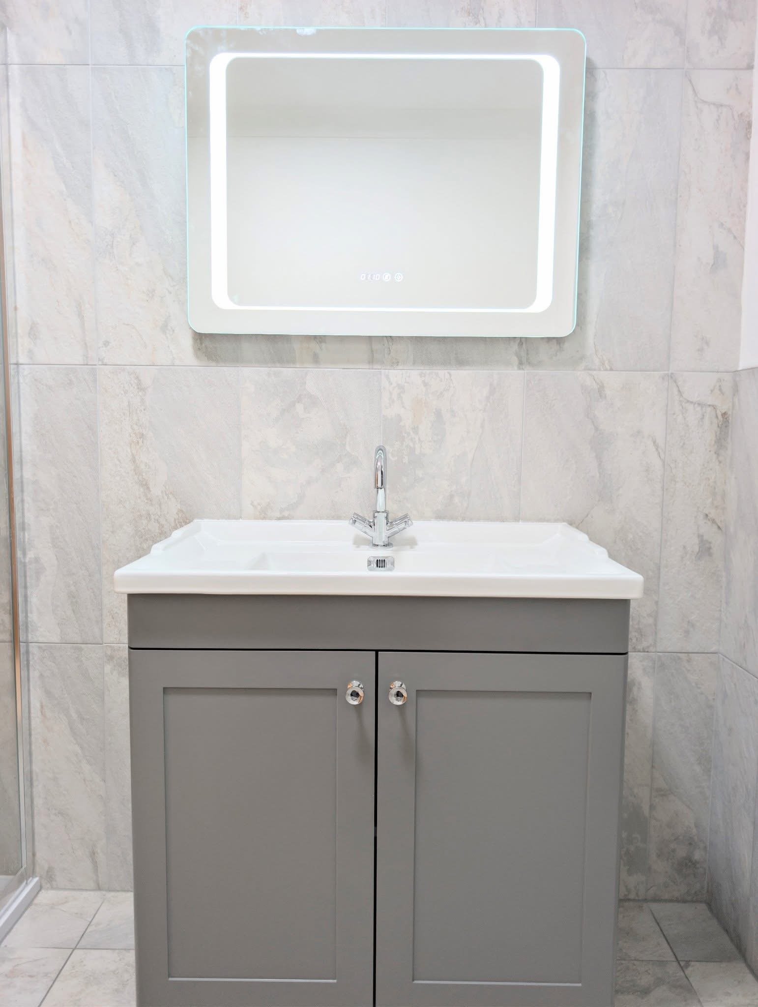 Bathroom vanity with a gray cabinet, white sink, silver faucet, rectangular mirror with LED lighting, and tiled walls.