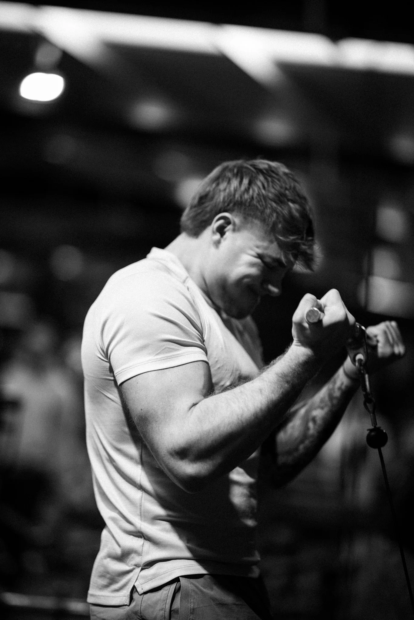 A young man in a T-shirt passionately singing into a microphone, with a blurred background.
